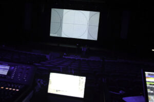 Theatre hall in preparation for show. Professional equipment and laptops glow on table in dark of theater hall on preparation before performance