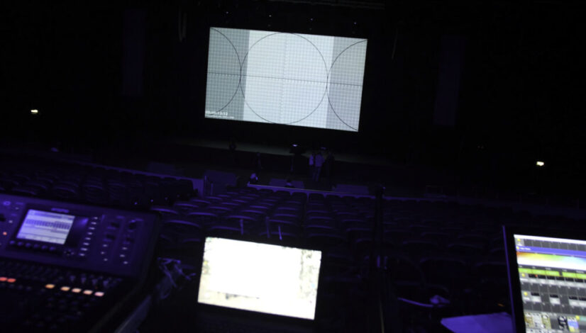 Theatre hall in preparation for show. Professional equipment and laptops glow on table in dark of theater hall on preparation before performance